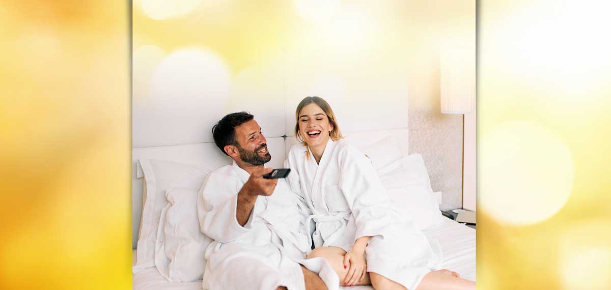 Two People in Robes Lounge on a Hotel Bed